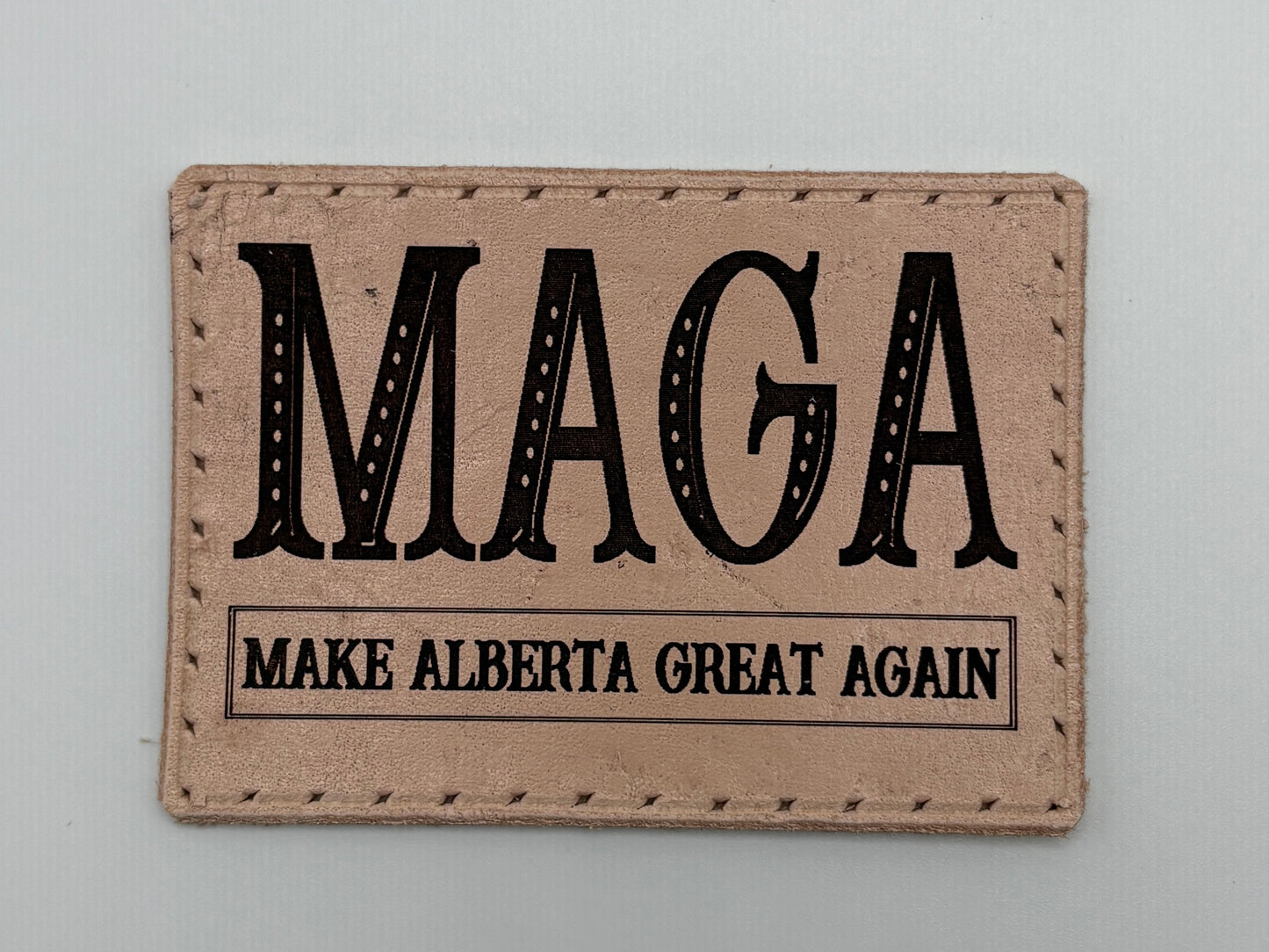 Rectangular patch with 'MAGA Make Alberta Great Again' text on a beige background