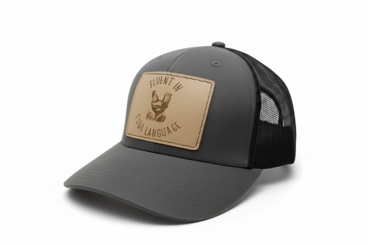 Gray cap with a brown leather patch featuring text and a rooster illustration on a light gray background