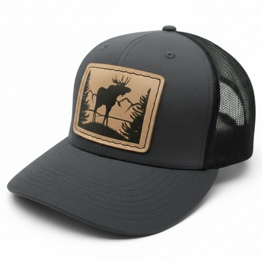 Gray trucker cap with a leather patch featuring a moose design on a white background
