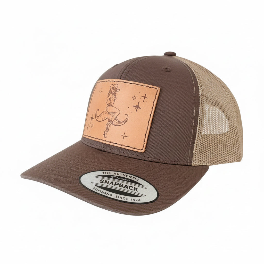 Brown and beige cap with a leather patch featuring a cowboy design on a cowhide background