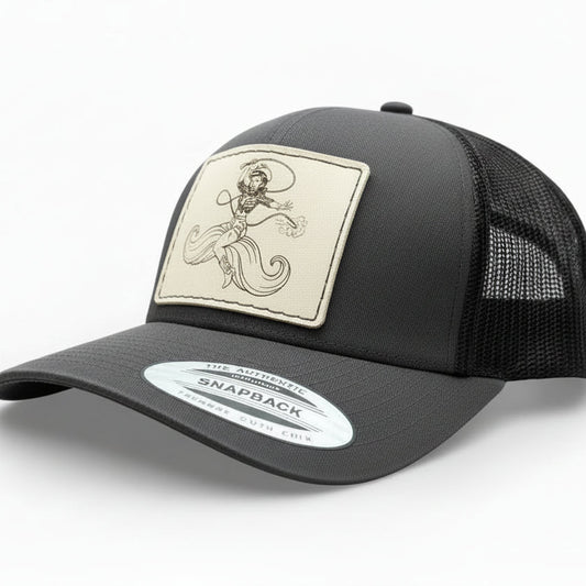 grey and black trucker hat with a decorative leather patch featuring a woman riding a moustache design.