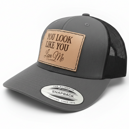 Gray trucker cap with a brown leather patch and label on a white background