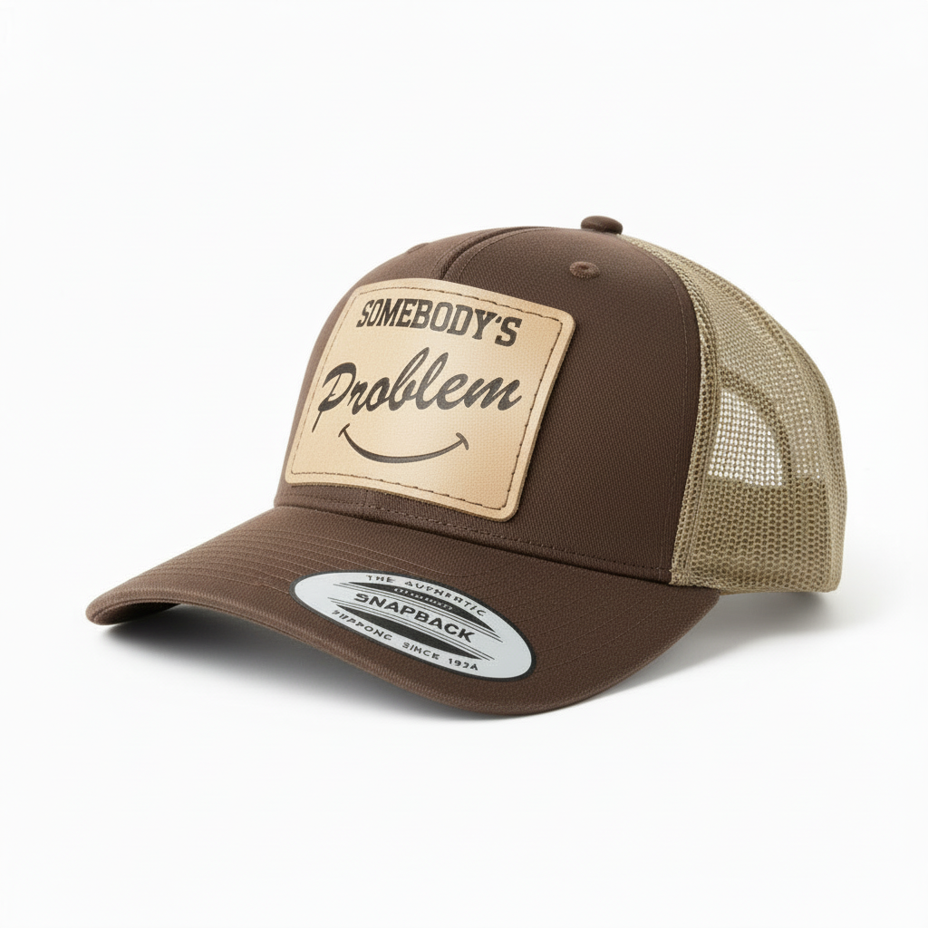 Gray and black trucker cap with leather patch and 'Somebody's Problem' text on a white background