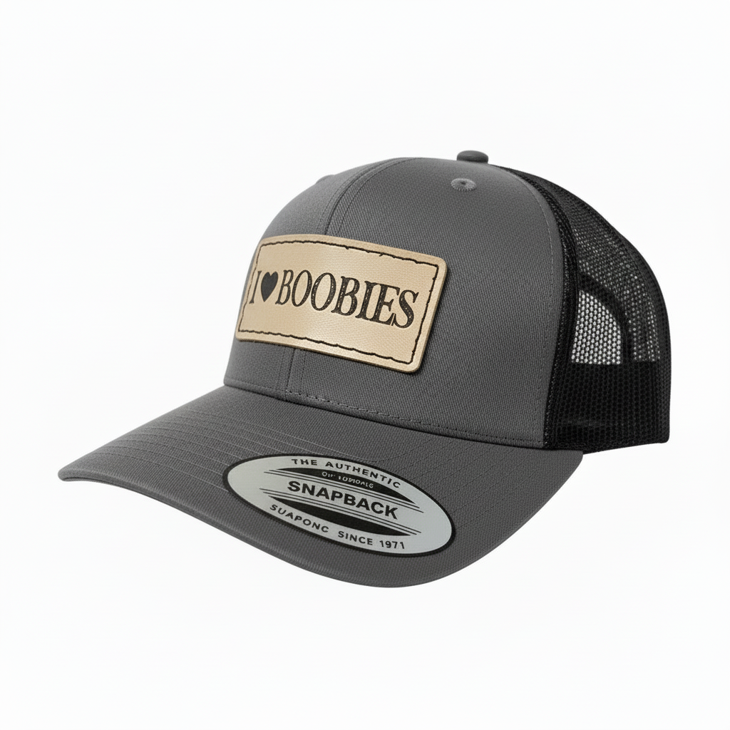 Black trucker cap with a tan patch displaying 'I ❤️ Boobies' on a white background