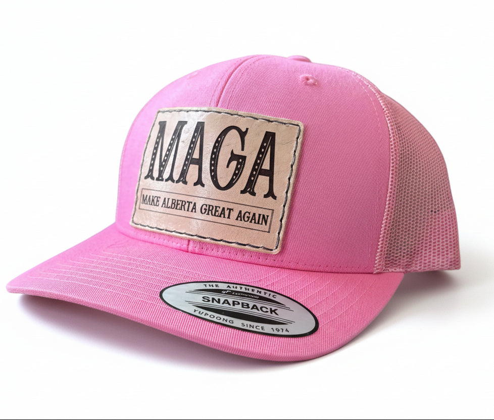 Pink cap with 'MAGA Make Alberta Great Again' patch on a white surface.