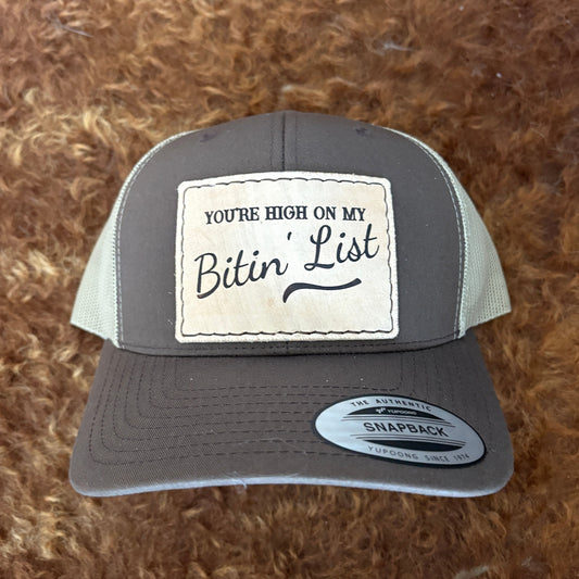 brown hat with a leather hat patch that says you're high on my bitin' list