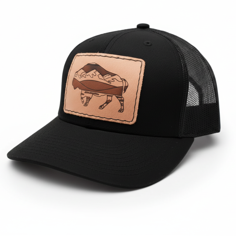 Black trucker cap with leather patch featuring a bear design on a white background