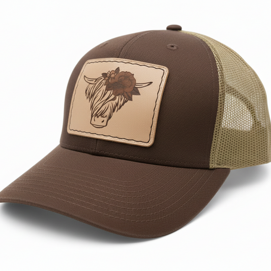 Brown and beige trucker cap with a leather patch featuring a bull's head on a white background