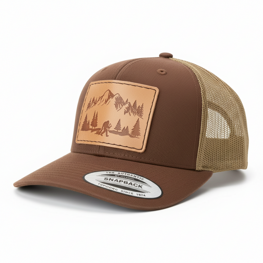 Brown and beige trucker cap with nature-themed patch on a white background