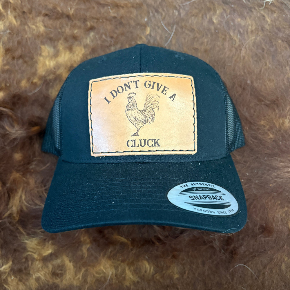 Black cap with a rooster patch and text on a brown textured background