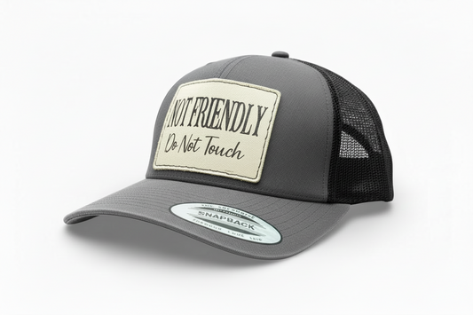 Gray and black trucker cap with a patch that says 'Not Friendly, Do Not Touch' on a white background