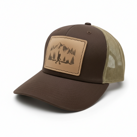 Brown and beige cap with a mountain and tree design on a white background
