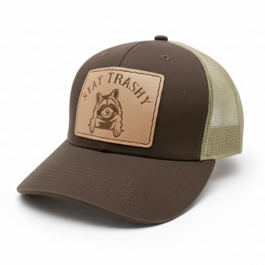 Brown and beige cap with 'Stay Trashy' patch featuring a raccoon on a white background