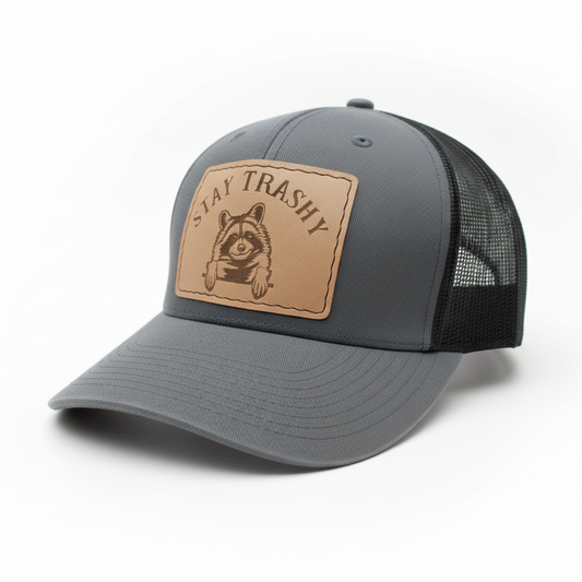 Gray cap with a brown leather patch featuring a raccoon and 'Stay Trashy' text on a white background.