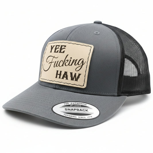 Gray and black trucker cap with a leather patch and brand logo on a white background