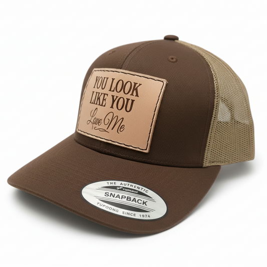 Brown and beige cap with leather patch and 'You Look Like You Love Me' text on a light gray background